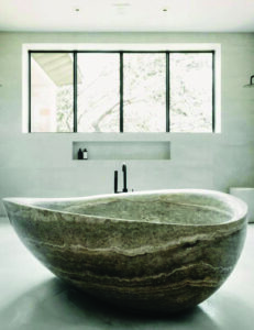 Freestanding bathtub carved from banded travertine in an organic curved shape