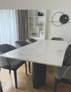 Rectangular white marble dining table with fine grey veining on a dark cylindrical base