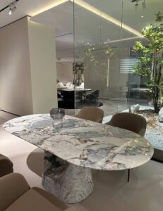 Oval marble dining table with a heavily veined top on a conical stone pedestal