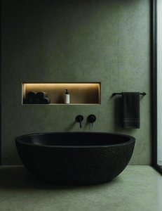 Oval freestanding bathtub in black stone with a textured exterior and smooth interior