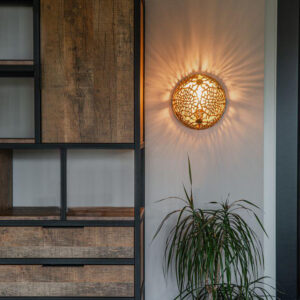 Round pierced metal wall light casting a patterned shadow